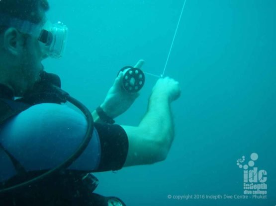 Diver reeling in the line after sending up an SMB at the end of a Deep Dive