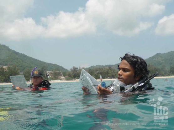 Open Water Instructor making notes for his debrief on the surface